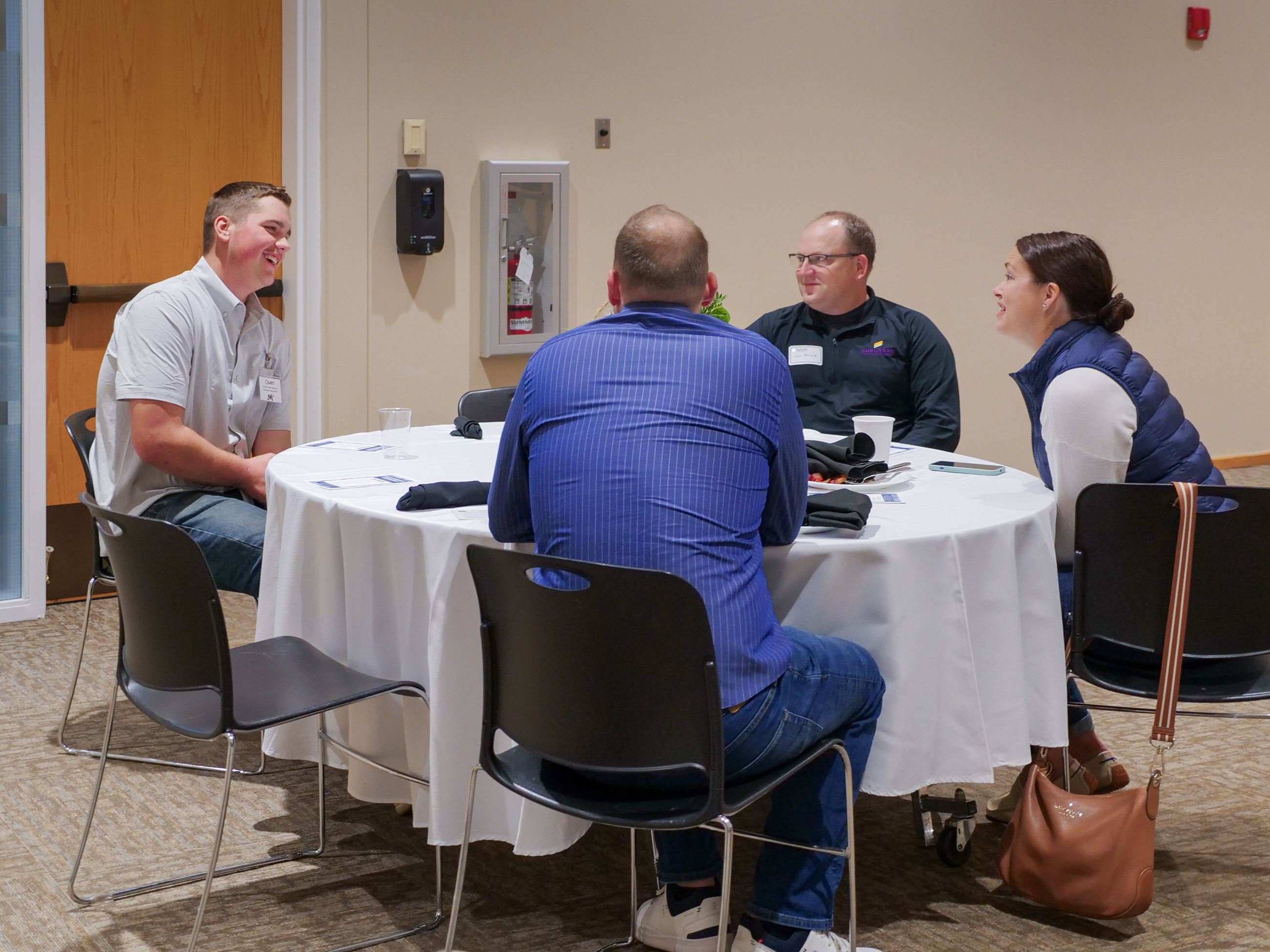 Manufacturers breakfast local professionals speaking with high school student.
