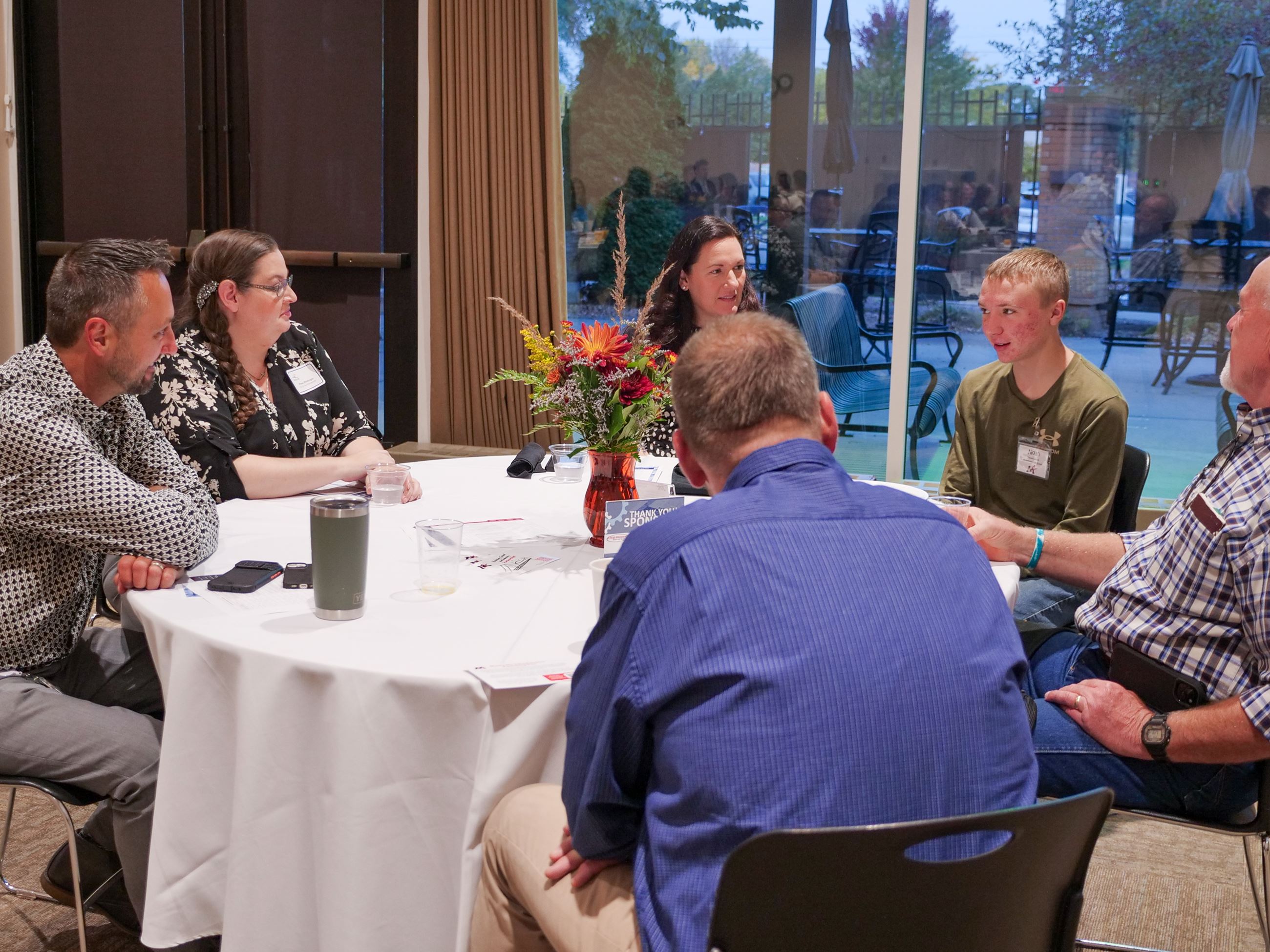 Manufacturers breakfast local professionals speaking with high school student.