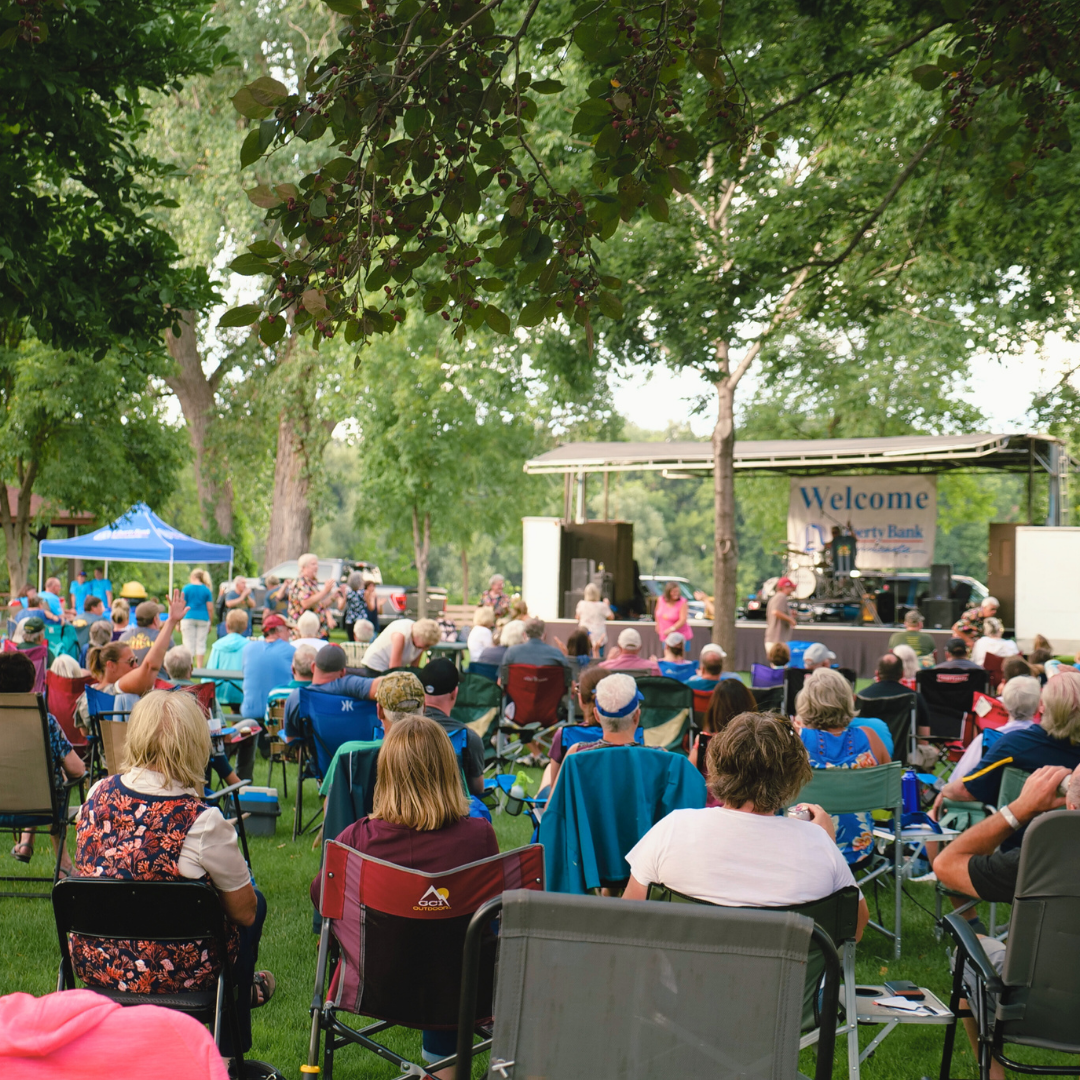 People in chairs listening to live music in a park.